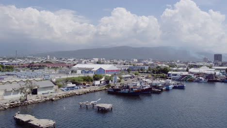 Aerial-view-of-the-old-dock-and-waterfront-in-Kinston-Jamaica-with-the-camera-turning-right-with-a-seagull-in-flight