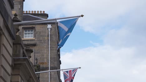 Bandera-Escocesa-Y-Británica-En-Astas-De-Fachada-En-Royal-Mile,-Edimburgo