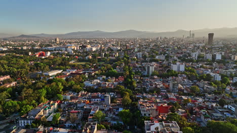 Mexico-City-Aerial-v13-cinematic-drone-fly-above-and-along-tree-lined-avenue-across-neighborhoods-at-sunset-with-sun-shinning-across-populous-residential-area---Shot-with-Mavic-3-Cine---December-2021