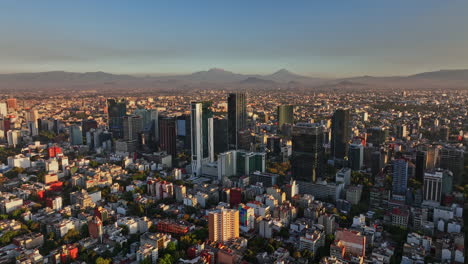 Mexico-City-Aerial-v21-dolly-in-shot-of-central-district-capturing-populous-downtown-cityscape-with-skyscrapers-and-mountainscape-background-at-sunset---Shot-with-Mavic-3-Cine---December-2021
