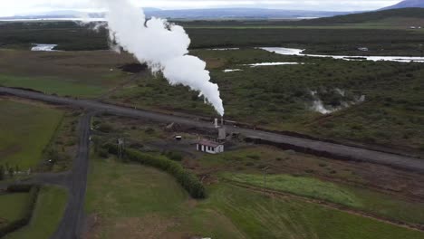 Hot-steam-coming-from-chimney-of-geothermal-volcanic-electricity-power-source,-aerial