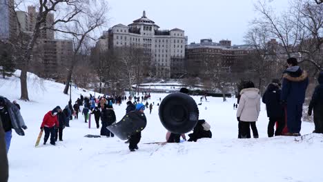 Slow-motion-sledders-climbing-hill-in-Central-Park,-New-York-City