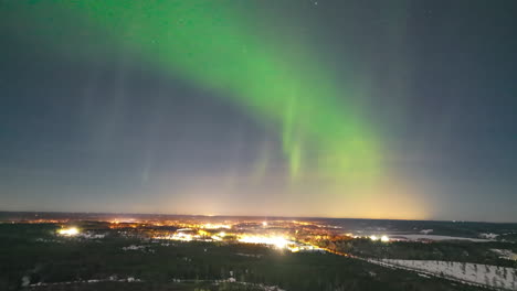 Northern-lights-dancing-over-a-town,-on-a-arctic,-autumn-night---aerial-Hyperlapse