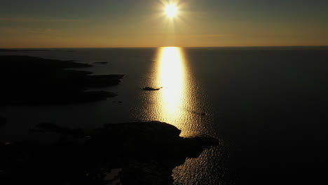 Aerial-view-of-silhouette-islands-and-the-reflecting-golden-hour-sun,-in-Aland,-Finland