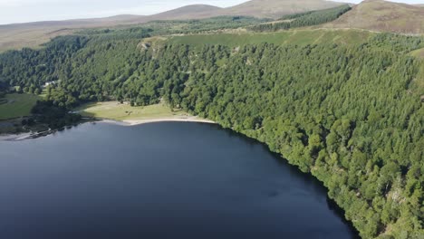 Beautiful-serene-landscape-of-Lough-Tay-Lake,-Guinness-Lake-in-the-Wicklow-Mountains,-with-the-green-forest-on-a-sunny-day-2