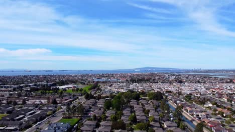 High-shot-over-neighborhood-with-ocean-and-mountain-the-background