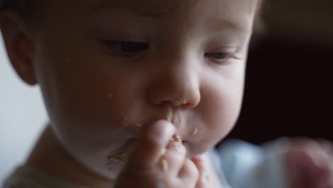 Cute-baby-girl's-chubby-hand-eating-food-in-highchair