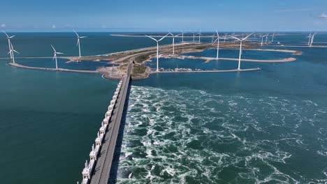 Drone-flight-over-surge-barrier-dam-and-wind-turbines-on-installed-on-island-during-sunny-day-in-Netherlands