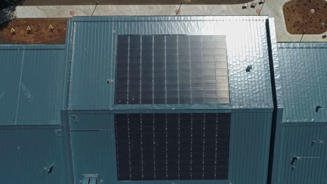 Rooftop-solar-panels-on-a-school-provide-clean,-renewable,-alternative-energy---descending-aerial-view