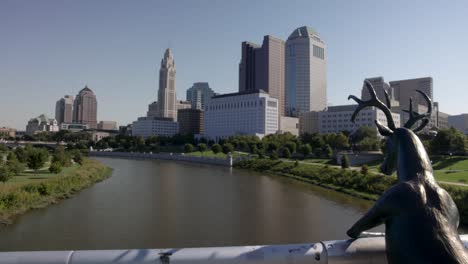 Deer-statue-on-Main-Street-Bridge-in-Columbus,-Ohio-with-skyline-in-background-panning-left-to-right