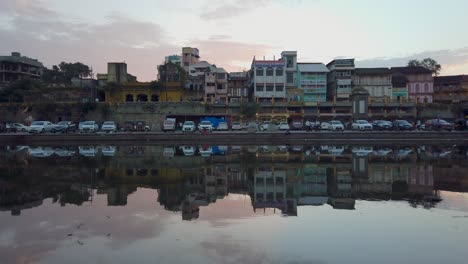 Parked-Vehicles-And-Buildings-On-The-Banks-Of-Godavari-River-At-Dusk-In-Ramkund,-Nashik,-India