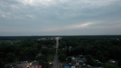 Aerial-drone-shot-over-residential-houses-along-a-main-highway-in-a-small-town-during-sunset