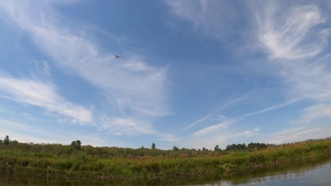 An-airplane-flies-overhead-of-a-river-channel-in-Lovewell-Pond-in-Fryeburg,-Maine