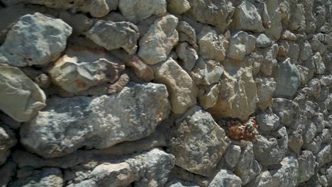 Right-dolly-slide,-frontage-built-with-large-raw-unworked-stones,-concrete-can-be-seen-between-the-boulders