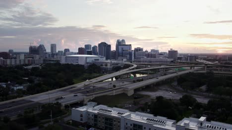 Drone-Shot-of-Downtown-Orlando-at-sunrise,-Interstate-4-in-foreground