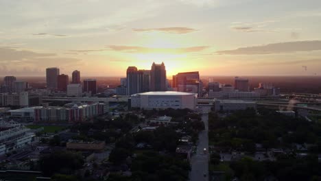 Panning-Drone-Shot-of-Downtown-Orlando-at-sunrise,-buildings-silhouetted-by-sun