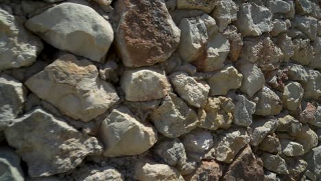 Right-dolly-slide,-facade-constructed-of-rough,-uncut-stones,-concrete-cladding-visible-amongst-the-rocks