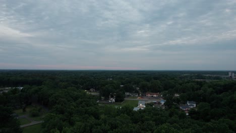 Aerial-drone-shot-over-houses-in-the-small-town-during-sunset-on-a-cloudy-evening