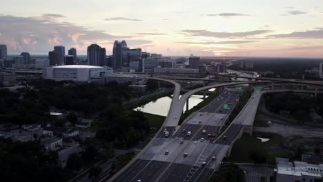 Push-in-Drone-Shot-of-Downtown-Orlando-at-sunrise,-flying-over-SR-408