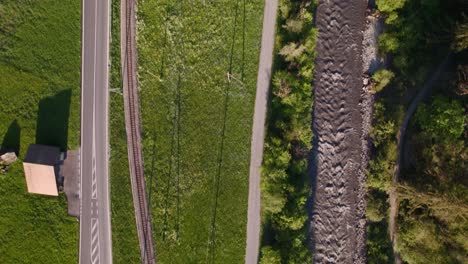 Aerial-drone-footage-top-down-view-of-road,-railroad-and-a-river-close-to-Grindelwald-in-Swiss-Alps