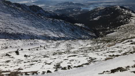 Push-forward-tilt-up-reveal-aerial-shot-over-an-endless-snow-covered-wild-mountain-range