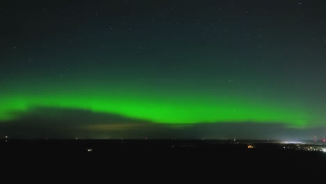 Aerial-view-of-Polar-lights-waves-floating-over-the-night-sky,-towards-a-city