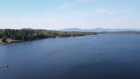 Aerial-drone-footage-panning-over-Lovewell-Pond-with-a-mountain-range-in-the-distance