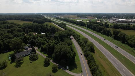 An-aerial-view-of-a-curved-road-by-farmland-with-many-trees-separating-them