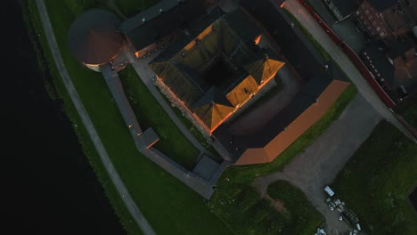 Aerial-view-of-the-Hame-or-Tavastia-castle,-summer-sunset-in-Hameenlinna,-Finland---reverse,-tilt,-drone-shot