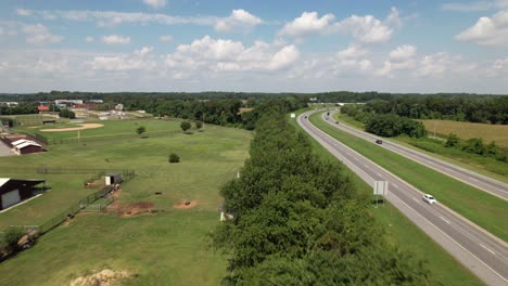 An-aerial-view-of-a-curved-road-next-to-an-open-field-with-a-line-of-trees-separating-them