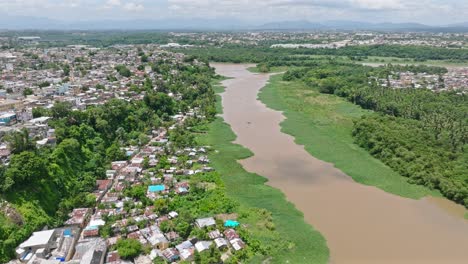 Aerial-flyover-neighborhood-located-beside-Rio-Ozama-River-in-Santo-Domingo-during-sunny-day