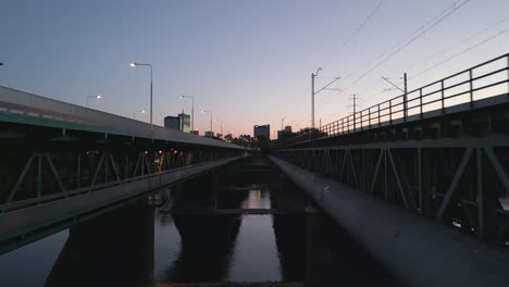 Vuelo-A-Través-Del-Medio-Del-Puente-De-Gdansk-Con-Vistas-Al-Panorama-Moderno-De-Varsovia-Durante-La-Puesta-De-Sol