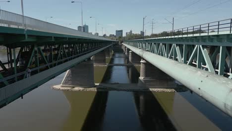 Unusual-drone-shot-of-a-multi-storey-bridge,-with-train-and-car-traffic-terminating-on-the-Warszawa-skyline