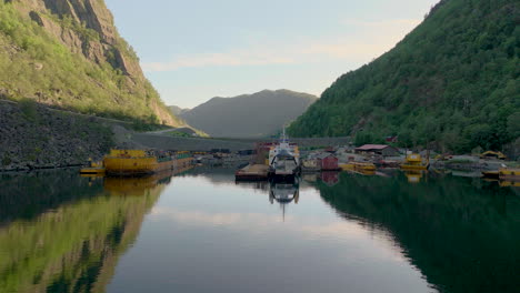 Norwegian-car-ferry-docked-at-industrial-harbor-for-reparations,-flat-calm-water-in-fjord,-aerial
