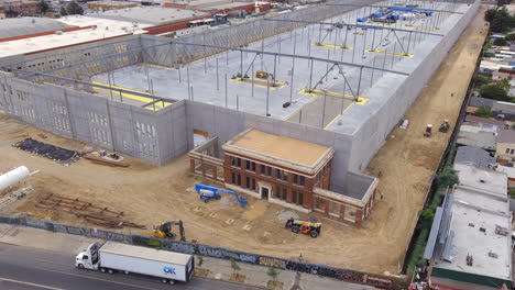 Construction-of-a-huge-warehouse-using-an-historical-structure-as-the-entrance---aerial-pull-back-reveal