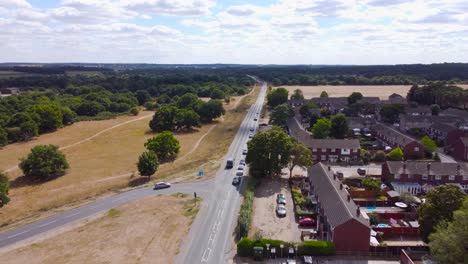 Aerial-footage-of-a-junction-revealing-traffic-as-the-drone-moves-towards-the-horizon-with-a-fantastic-view-of-a-forest,-then-the-Housing-Estate-in-Norfolk,-England