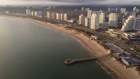 Vista-Aérea-Sobre-La-Playa-De-Arena-Y-La-Costa-De-Punta-Del-Este-Durante-El-Día-Soleado-Con-Niebla-En-El-Aire---Grandes-Edificios-Con-Vista-Al-Mar-En-Uruguay