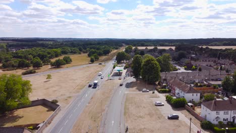 Aerial-footage-of-a-busy-road-with-cars-and-lorries-coming-up-and-down-also-revealing-vast-forest-and-housing-estates-in-Norfolk,-England