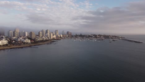 Aerial-panoramic-shot-of-Punta-del-Este-City-with-sandy-beach,skyline-and-harbor-with-boats