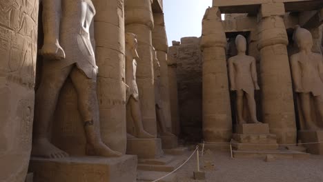 Pan-Down-View-Looking-Up-At-Sandstone-Columns-And-Statues-In-Between-At-Karnak-Temple-Complex-In-Egypt