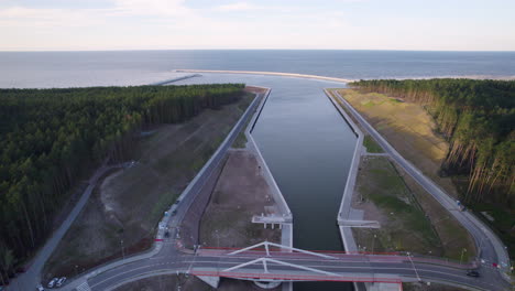 Drone-trucking-shot-of-Nowy-Swiat-Canal-for-ships-and-asphalt-bridge-between-forest-trees