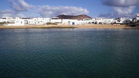 Video-of-a-coast-in-La-Graciosa-in-Spain-where-the-wind-is-blowing-and-there-are-white-buildings-and-houses-while-the-horizon-is-visible-in-the-distance-taken-during-a-sunny-day-with-clouds