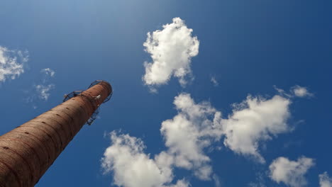 Alter-Schornstein-Mit-Flauschigen-Wolken-Und-Blauem-Himmel-Im-Hintergrund