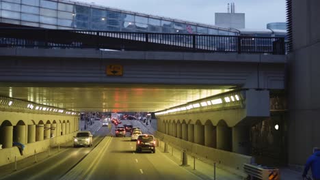 Driving-towards-tunnel-with-passenger-train-riding-on-overpass-in-Toronto,-Canada