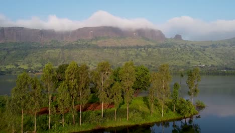 árboles-En-El-Islote-Con-Reflejo-Difuso-En-El-Lago,-Con-Pintorescas-Montañas-Al-Fondo