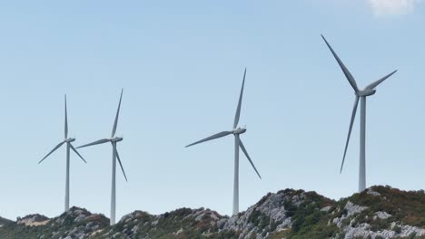 Aerial-view-in-front-of-wind-power-turbines,-on-top-of-a-mountain---tracking,-drone-shot