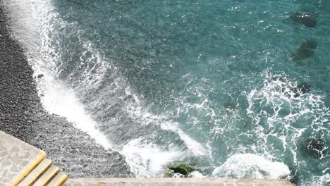Above-shot-of-crashing-waves-on-a-black-stone-beach