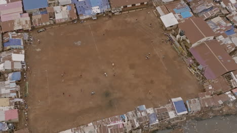 Slow-aerial-footage-that-is-zooming-out-of-people-walking-around-an-empty-soccer-field-in-Freetown,-Sierra-Leone