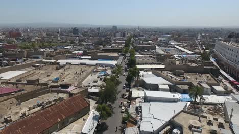 Eine-Luftaufnahme-Der-Stadt-Erbil-Mit-Der-Alten-Zitadelle-Von-Erbil-Und-Dem-Garten-Gegenüber-Dem-Schloss-Mit-Wasserfontänen-Und-Dem-Beliebten-Markt-12