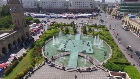 Eine-Luftaufnahme-Der-Stadt-Erbil-Mit-Der-Alten-Zitadelle-Von-Erbil-Und-Dem-Garten-Gegenüber-Dem-Schloss-Mit-Wasserfontänen-Und-Dem-Beliebten-Markt-9